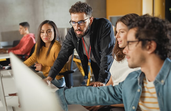 Instructor mentoring students at a computer lab