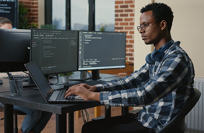 Person coding on multiple computers and laptops